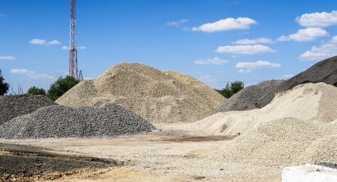 Large hills and piles of sand, gravel, crushed stone of white, gray and black color.