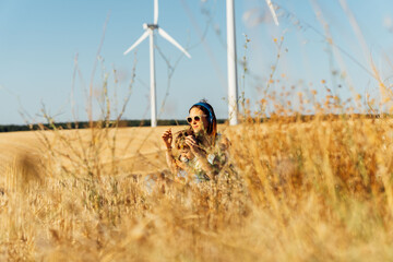 Young beautiful middle-aged mother mother sitting in cereal field with her three-year-old son hiding among the wheat wearing sunglasses and helmets