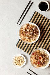 Two portions of Kung Pao chicken on a bamboo black and white napkin. Vertical top view on a light gray background