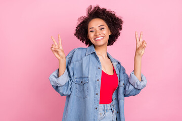 Photo of friendly cute african lady show v-sign wear jeans jacket red top isolated pink color background