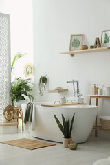 Fototapeta na wymiar Stylish bathroom interior with modern tub, houseplants and beautiful decor. Home design