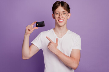 Photo of handsome cheerful man indicate finger credit card recommend advice choice isolated on violet color background