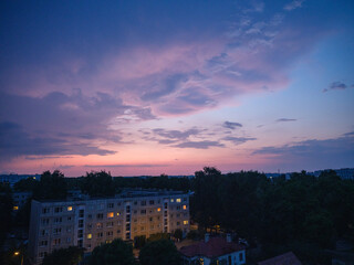 Fototapeta premium Dramatic red and dark blu clouds over city rooftops