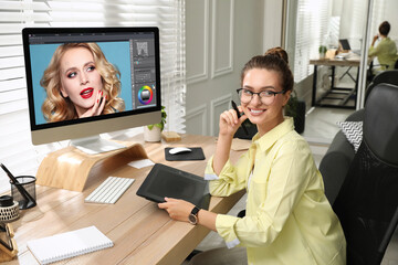 Professional retoucher working on graphic tablet at desk in office