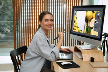 Professional retoucher working on graphic tablet at desk in office