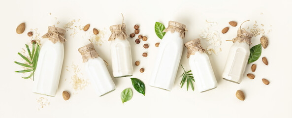 on dairy plant based milk in bottles and ingredients on light background. Alternative lactose free milk substitute, flat lay - obrazy, fototapety, plakaty