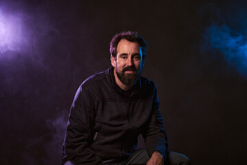 attractive man with smoke and lights in the background. Portrait in studio
