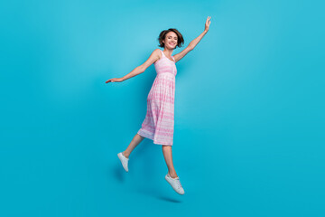 Fototapeta premium Full size profile photo of carefree young lady run wear pink dress sneakers isolated on blue background