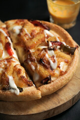 the close up view of the tempting pizza with a cheese sauce beside. a baked Italian food on black suitable for advertisement or any element design.