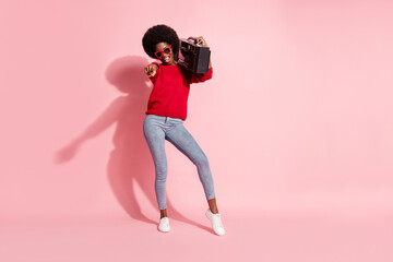 Fototapeta na wymiar Full body photo of brown haired of afro american lady wear jeans point you hold boombox isolated on pink color background
