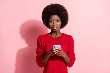 Photo of scared young afro american woman hold smartphone addicted user isolated on pink color background