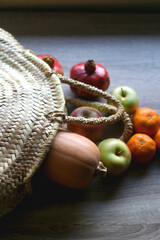 Straw tote bag filled with butternut squash and various fruit. Selective focus.