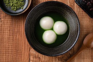Matcha big tangyuan and matcha soup on wooden table.