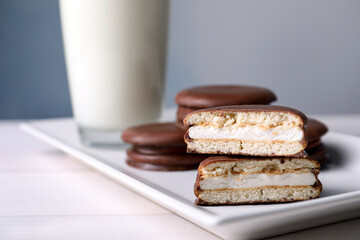 Tasty choco pies and milk on white wooden table, closeup view. Space for text