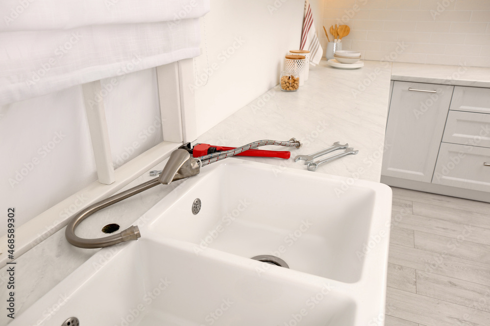 Poster Plumber's tools and water tap ready for installation near sink on countertop in kitchen