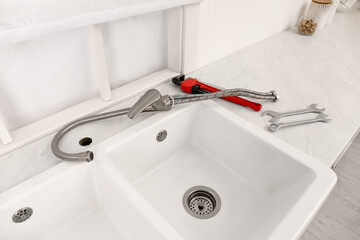 Plumber's tools and water tap ready for installation near sink on countertop in kitchen