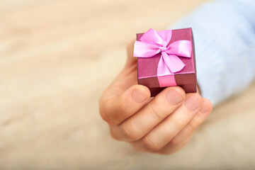 Man's hand in shirt giving pink gift. hand giving gift box with pink ribbon. copy space. Pleasant little thing