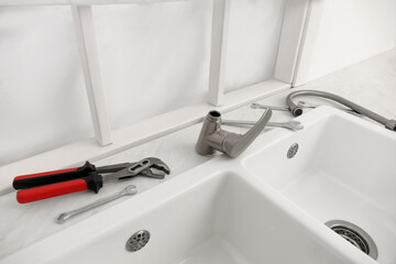 Plumber's tools and water tap ready for installation near sink on countertop in kitchen