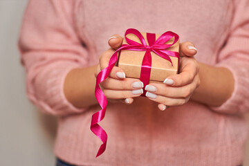 female hands giving a gift. presentation of a gift box with a pink ribbon. space for copying. Nice little thing
