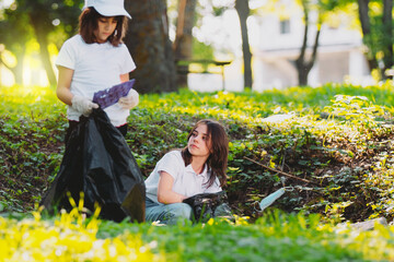 Close up photo of two young girls volunteer participate in cleaning the nature from the rubbish,...