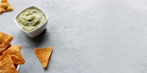 Guacamole smooth avocado dip to eat with nachos snack. Background banner with copy space.