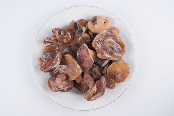 Frozen mushrooms close-up isolated on white plate, brown champignon prepared for cooking