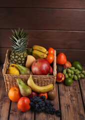 Mix of fresh juicy colorful exotic tropical fruits in basket on wooden background