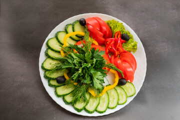Assorted fresh vegetables on a plate .Dish of cucumbers, paprika, tomato and basil with parsley and cucumber
