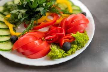 Assorted fresh vegetables on a plate .Dish of cucumbers, paprika, tomato and basil with parsley and cucumber