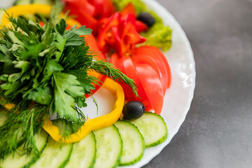 Assorted fresh vegetables on a plate .Dish of cucumbers, paprika, tomato and basil with parsley and cucumber