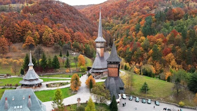 Aerial drone view of the Barsana Monastery, Romania. Main church and other buildings, visitors, hills covered with yellowing forest around