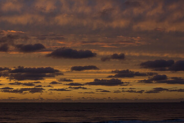 Naklejka premium Yellow and orange sunset. Sunset in the ocean with a lot of clouds