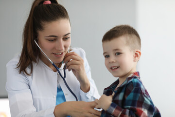 Doctor pediatrician listening to heart with stethoscope to little boy in clinic