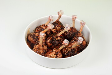 Uncooked group of chicken lollipops marinated with spices on white plate, Fried chicken legs recipes 