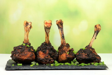 Three fried chicken lollipops on a black stone plate, Fried chicken legs