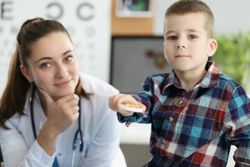 Little boy holding yellow gelatin capsules at doctor appointment