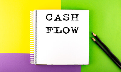 Minimal work space : sketchbook on the colorful background with CASH FLOW text
