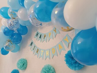 Birthday decorations on the white wall white and blue balloons with confetti and the inscription