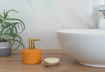 Soap dispenser near the sink in the bathroom. A dispenser for shampoo or soap made of glass with a pump on a background of marble tile stone. Organic spa cosmetic with aloe vera