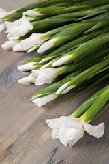 Several blooming white irises lie on a dark wooden background.