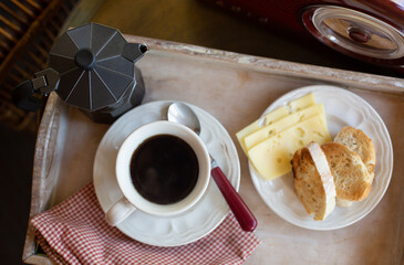 A breakfast tray with a fried toast, a cup of black coffee and a coffee pot is on a table near with radio. Retro style.