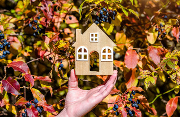 The symbol of the house in the girl's hand on the background of red leaves
