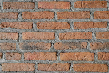 Red brick block interior wall with rough surface on plain area. Building material object for background and texture.