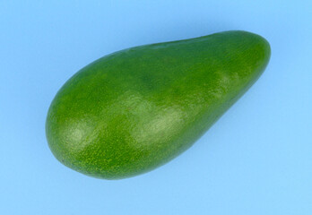 A green avocado fruit with a rough skin and light from the lamps