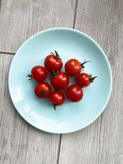 Fresh vegetables: red cherry  tomatoes on the blue plate. Top view.