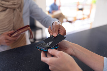Biracial woman paying with credit card at reception at modern dental clinic