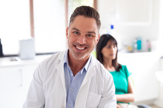 Portrait of smiling caucasian male dentist looking at camera at modern dental clinic