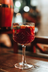 Crystal glass of hot mulled red wine with fresh fruits and spices on a wooden table