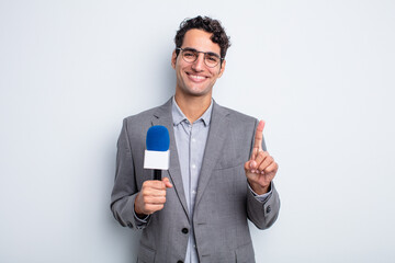 young handsome man smiling proudly and confidently making number one. presenter with microphone