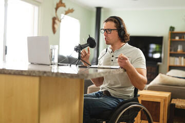Caucasian disabled man recording podcast using microphone sitting on a wheelchair at home
